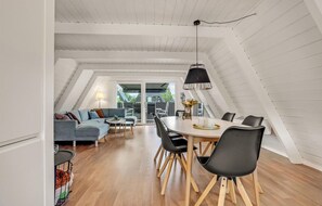 Enjoy meals in this spacious loft-style room with a large dining table and balcony overlooking lush greenery.