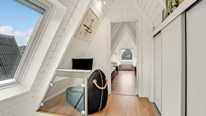 A narrow, sloped ceiling room with a bed, a TV, and a bag on a shelf. - 2 bedroom cozy home in Farsø (Farsø)