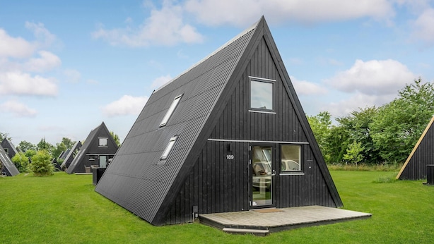 A modern, triangular-shaped building with a flat roof, a small porch, and a visible door. - 2 bedroom cozy home in Farsø (Farsø)