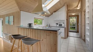 A modern kitchen with wooden accents, a large island, and a view of greenery outside. - Gorgeous home in Rødby with WiFi (Rødby)