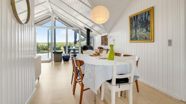 Un coin repas avec une table dressée pour deux personnes, une grande fenêtre et un tableau accroché au mur.