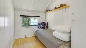 Une petite pièce avec un lit superposé, une fenêtre donnant sur un véhicule à l’extérieur et une étagère avec des objets décoratifs.