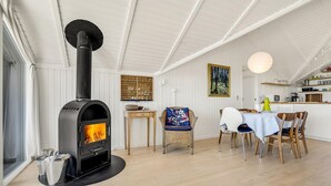 Une cuisine moderne équipée d’un poêle à bois, d’un coin repas avec une table et des chaises, et d’un comptoir de cuisine agrémenté de divers objets.