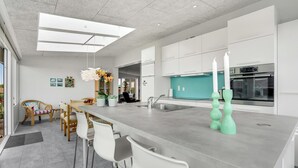 Een moderne keuken met een groot eiland, witte kastjes en een turquoise spatwand.