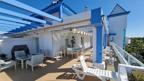 A covered outdoor patio with white furniture, a dining area, and a staircase leading to an upper level. - Costa Ballena Penthouse with bbq and WIFI (Rota)