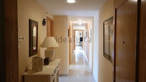 A hallway with a wooden door, a mirror, a lamp, and a framed picture on the wall. - Costa Ballena Penthouse with bbq and WIFI (Rota)