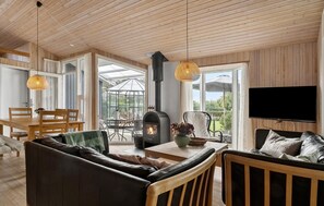 A cozy living room with a fireplace, wooden furniture, and a TV mounted on the wall.