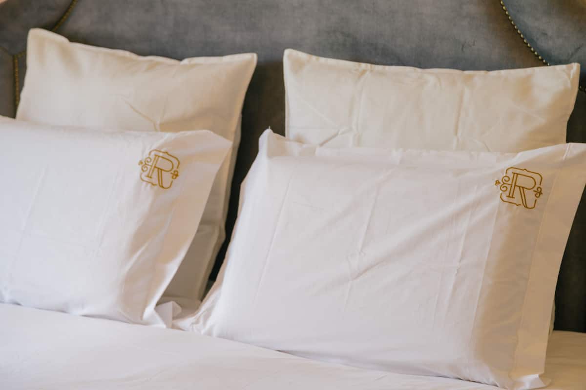 A bed with white pillows and a grey headboard.