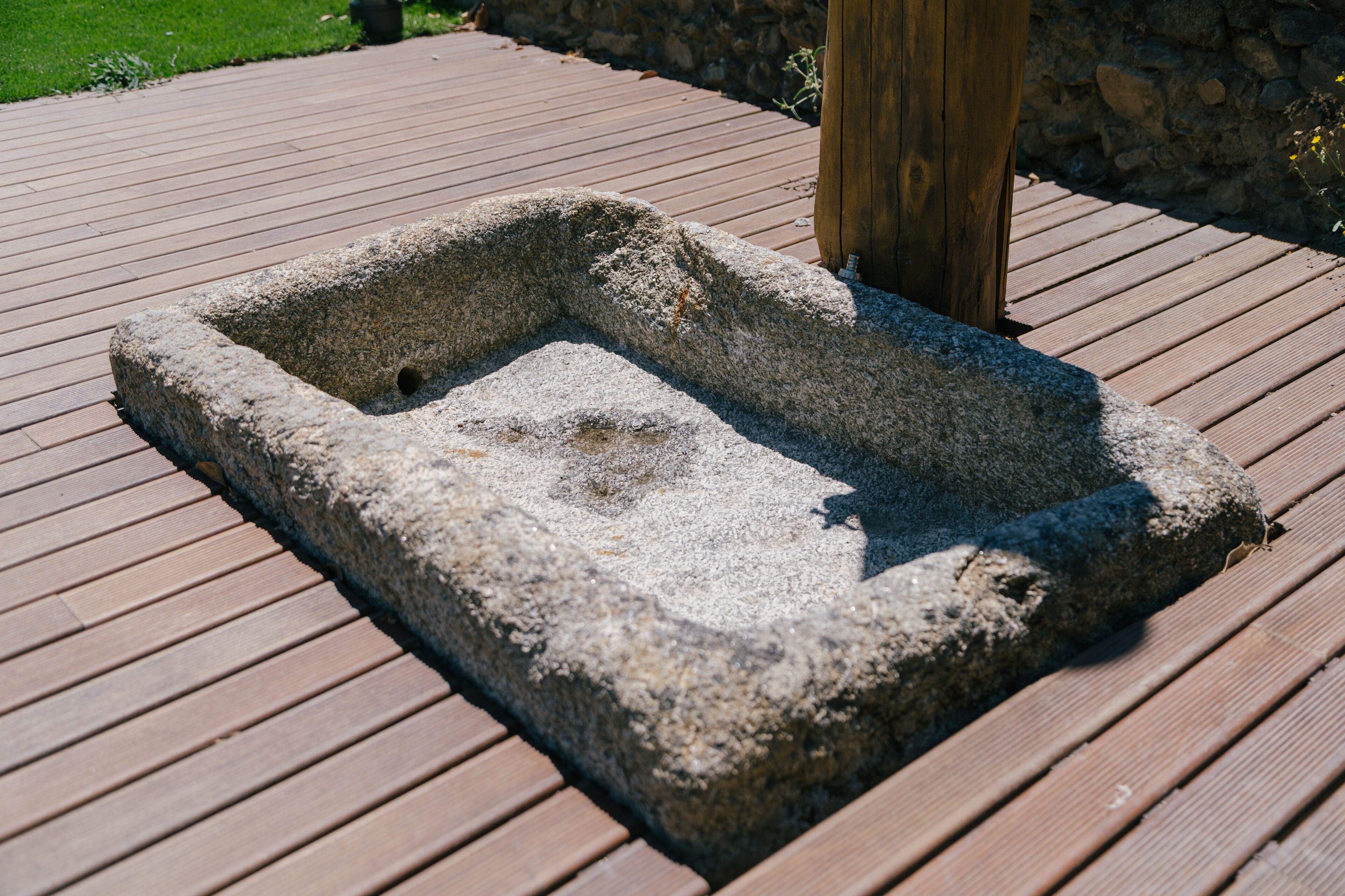A stone planter box on a wooden deck.