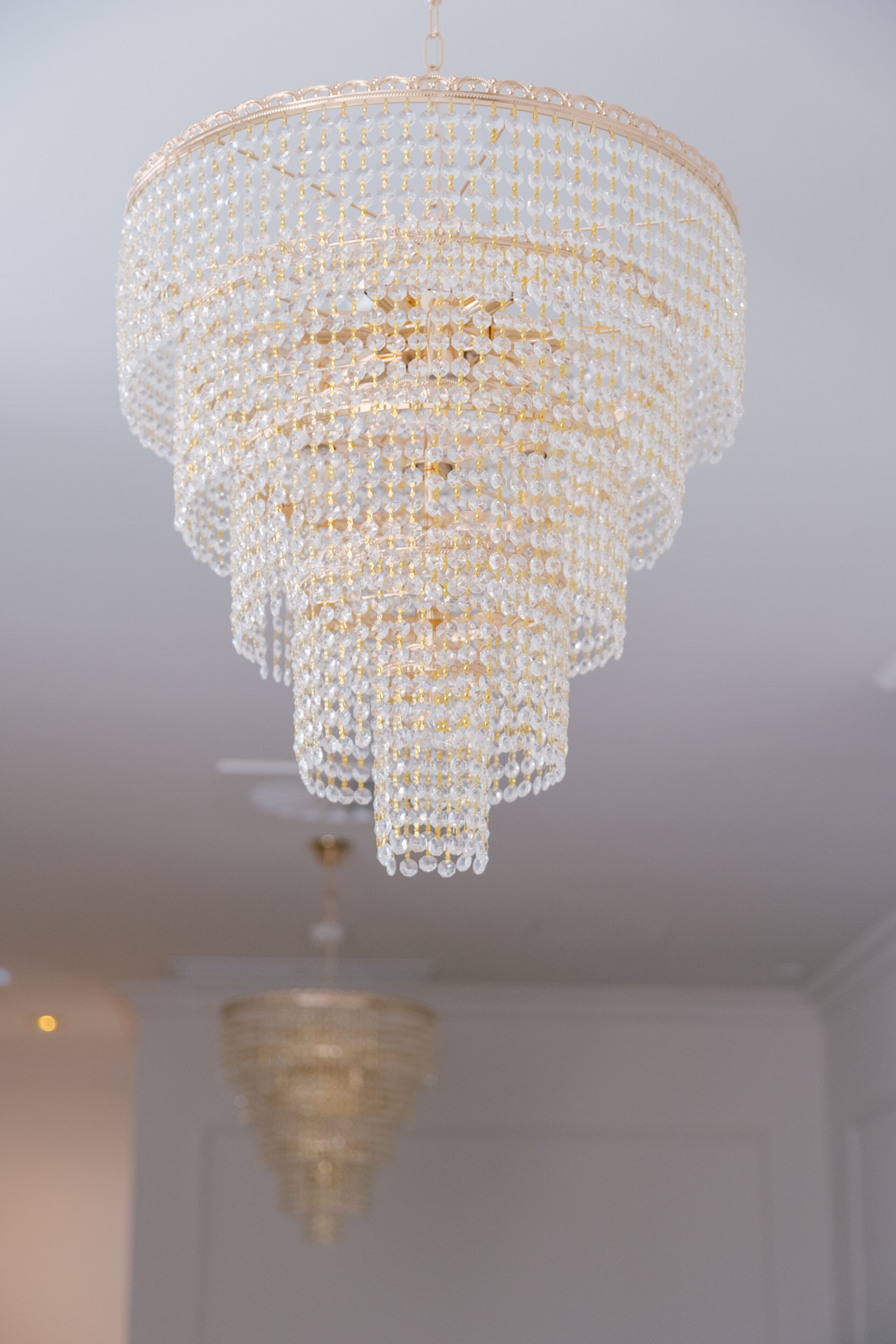 A chandelier with multiple tiers of clear crystals and gold accents.