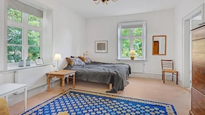A bedroom with a bed, bedside table, lamp, chair, and a chandelier. - 6 bedroom gorgeous home in Kværndrup (Kværndrup)