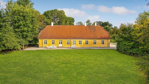 A yellow house with a red roof and white windows, surrounded by a green lawn and trees. - 6 bedroom gorgeous home in Kværndrup (Kværndrup)