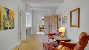A hallway with a wooden floor, a table with a lamp, leather chairs, and artwork on the walls. - 6 bedroom gorgeous home in Kværndrup (Kværndrup)