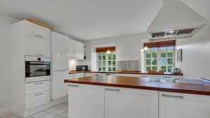 A modern kitchen with white cabinetry, a Bosch oven, a microwave, and a wooden countertop. - 6 bedroom gorgeous home in Kværndrup (Kværndrup)