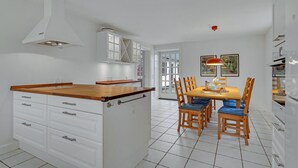 A modern kitchen with white cabinetry, a wooden countertop, and a dining area with a table and chairs. - 6 bedroom gorgeous home in Kværndrup (Kværndrup)