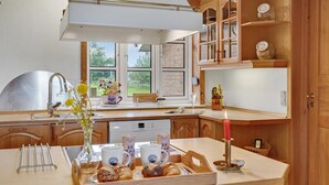 A kitchen with wooden cabinets, a large window, and a breakfast setup including croissants and coffee mugs. - Gorgeous home in Lemvig with WiFi (Lemvig)