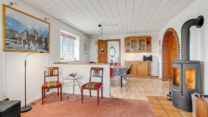 A cozy living room with a fireplace, a dining area, and a kitchen with wooden cabinets. - Gorgeous home in Lemvig with WiFi (Lemvig)
