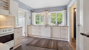Una cocina moderna con armarios blancos, horno empotrado y ventana con vistas a zonas verdes.