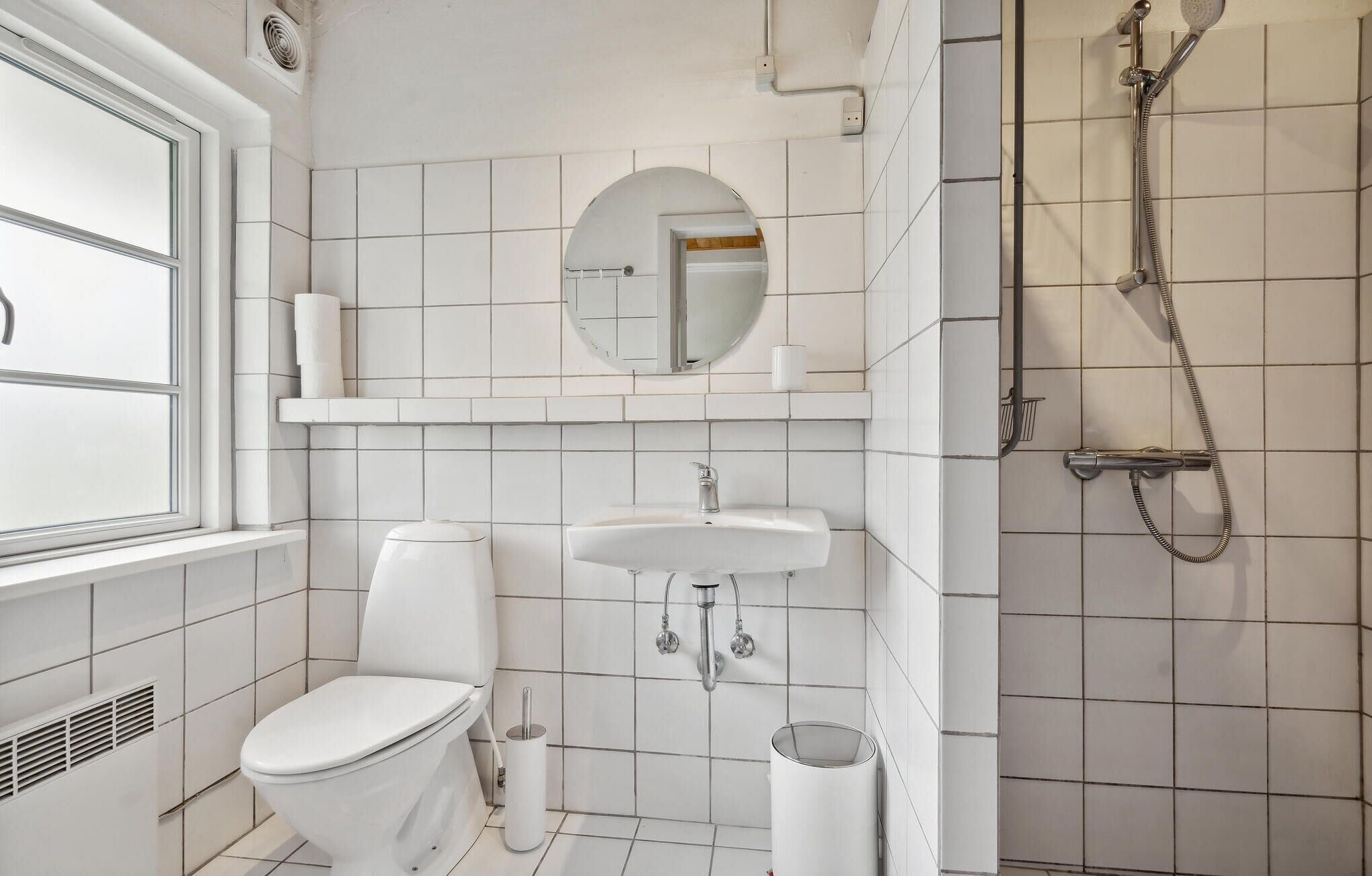 A modern bathroom with a toilet, sink, and shower.