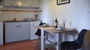 Eine kleine Küche mit weißen Schränken, einer gefliesten Spritzschutzleiste und einer Essecke mit Tisch für zwei Personen.