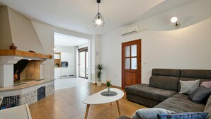 Un salon moderne avec une cheminée, un canapé, une table basse et, au fond, un coin repas.