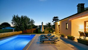 Une piscine avec des chaises longues et un espace patio.