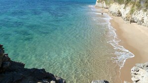 A coastal beach with clear waters, a sandy shore, and rocky cliffs. - Villa Muscari Nature 200 meters from the beach 10 pax (Los Caños de Meca)