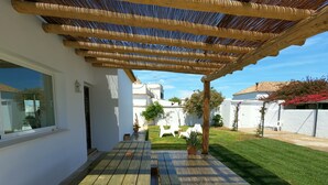 A covered patio with wooden benches and a pergola.