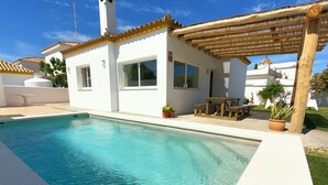 A swimming pool with a pergola and outdoor seating area.