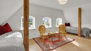 A room with a sloped ceiling, two beds, a dining table with chairs, and a large window. - 3 bedroom nice home in Kværndrup (Kværndrup)