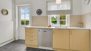A modern kitchen with a dishwasher, wooden cabinets, a window with a view, and a hanging light fixture. - 3 bedroom nice home in Kværndrup (Kværndrup)