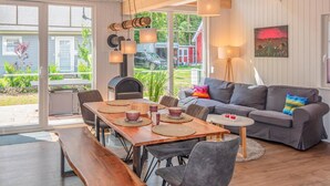 A modern living room with a dining area, a grey sofa, and a wooden bench.