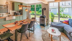A modern kitchen with a dining area, a fireplace, and a cozy seating area with a sofa and a small table.