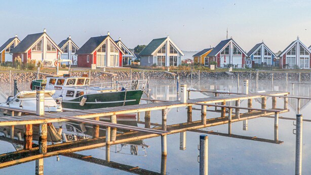 A waterfront property with a dock and several houses with distinct architectural styles.