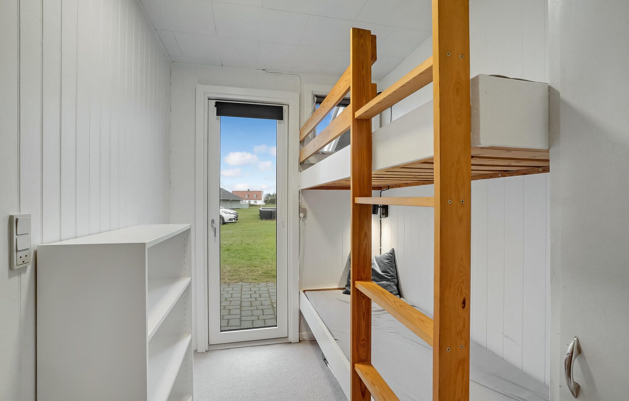 Una habitación pequeña con una litera y una puerta que da al exterior.
