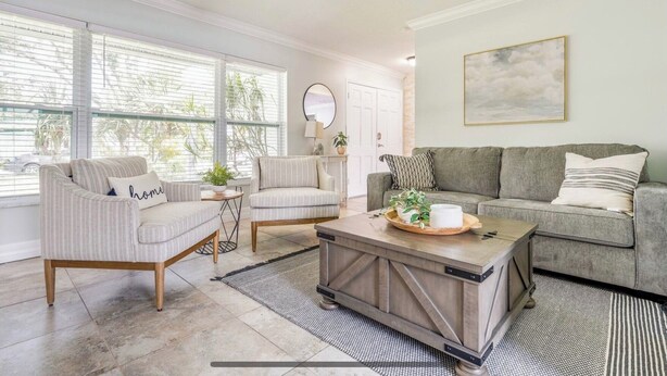 Un salon comprenant un canapé, deux fauteuils, une table basse et un ventilateur de plafond.