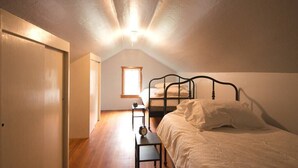 Une chambre avec un plafond en pente, un lit, une table de chevet et une fenêtre.