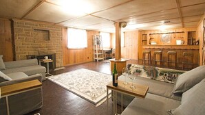 Un salon chaleureux avec un mur en pierre, des meubles en bois et un coin bar.