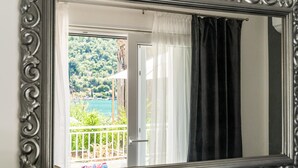 Une pièce dotée d’un grand miroir qui reflète un balcon donnant sur un paysage verdoyant et un plan d’eau.
