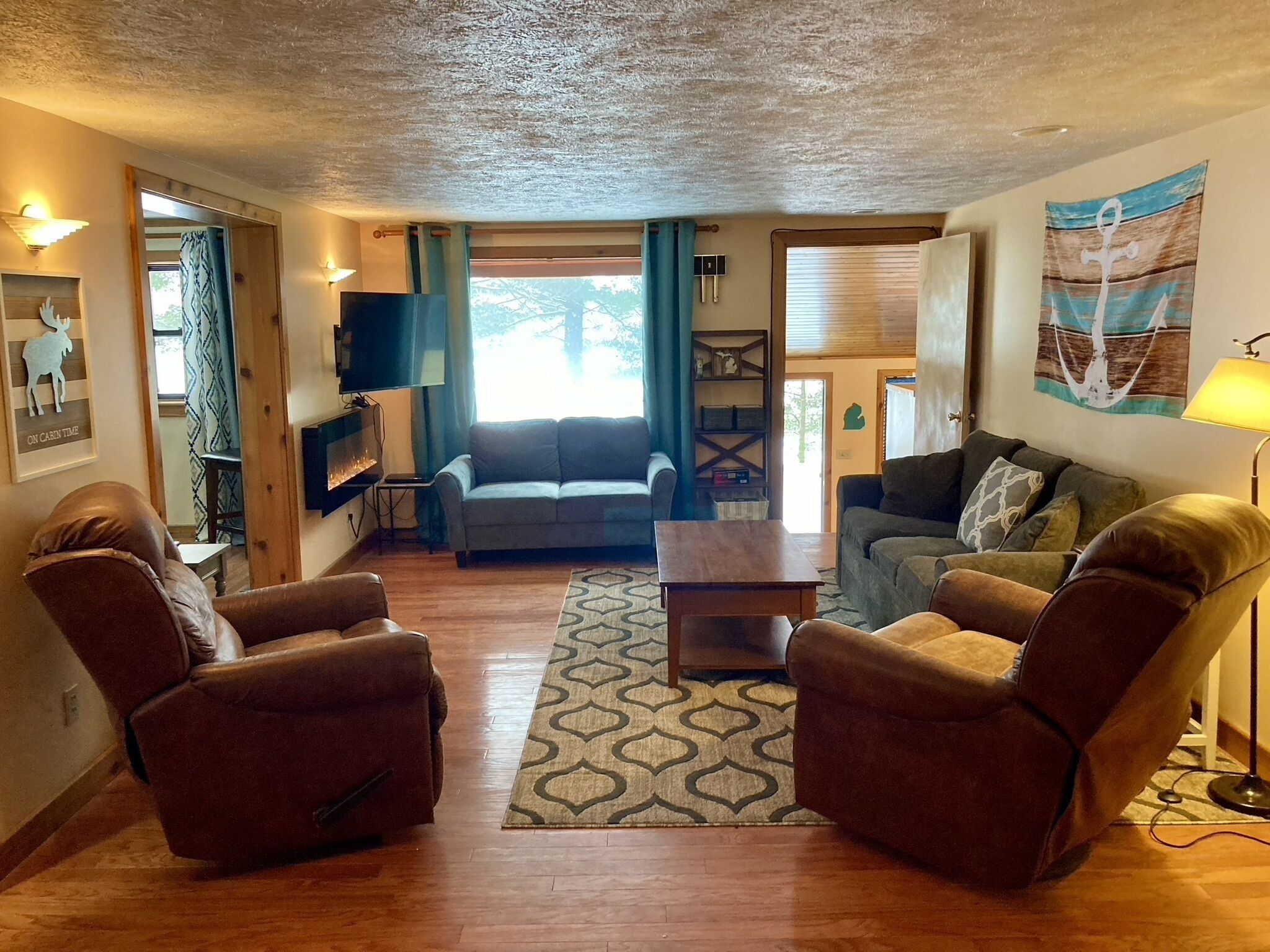A cozy living room with a fireplace, two leather armchairs, a sofa, and a coffee table.