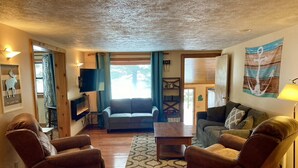A cozy living room with a fireplace, two leather armchairs, a sofa, and a coffee table. - Fall Splendor! Cozy Cabin, Lake Views & Campfires! (Cadillac)