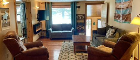 A cozy living room with a fireplace, two leather armchairs, a sofa, and a coffee table.