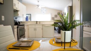 A dining table with yellow placemats, a potted fern, and a tablet.