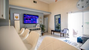 Relax in this stylish living space with a flat-screen TV, comfortable seating area, and a large mirror.