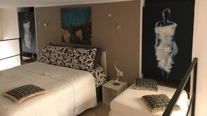 A bedroom with two beds, a nightstand, and wall art. - San secondo street (Torino)