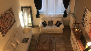 A living room with a white sofa, a wooden coffee table, and a large mirror. - San secondo street (Torino)