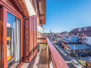 Un balcon donnant sur une rue et des immeubles, dont le clocher d’une église.
