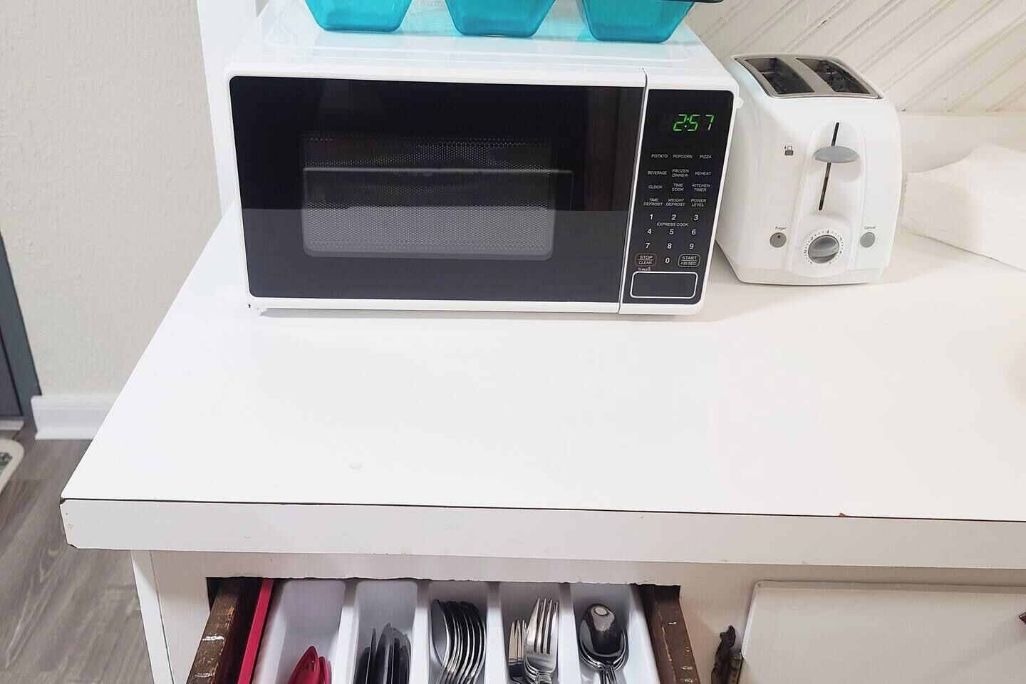 Een keuken met een magnetron en broodrooster op een wit aanrecht.
