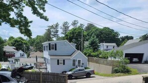 A wooden deck with two wicker chairs and a glass table. - 4 min walk to the beach. 1BD. Pets Ok FREE parking (Old Orchard Beach)