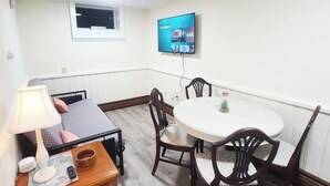 A small room with a bed, a table with chairs, a TV mounted on the wall, and a window. - 4 min walk to the beach. 1BD. Pets Ok FREE parking (Old Orchard Beach)
